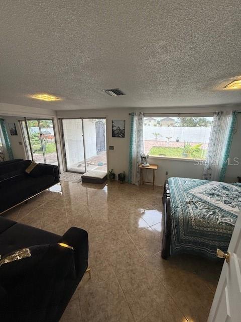 2013 Marilyn Ave, Winter Haven, FL 33881 - bedroom with access to exterior, light tile patterned flooring, and a textured ceiling