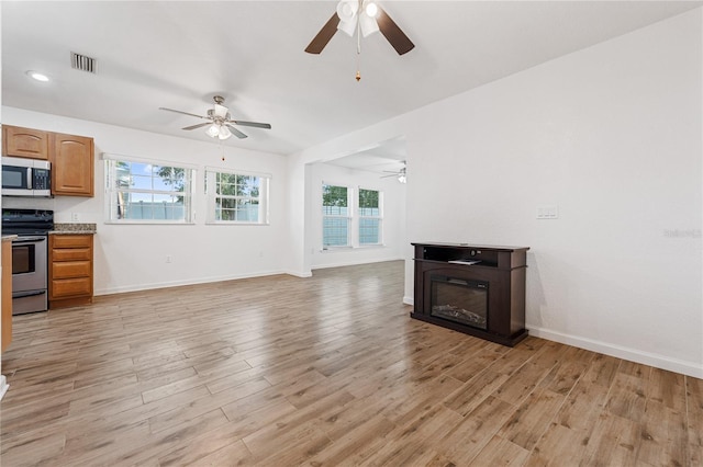 2343 St George Dr, Davenport, FL 33837 - unfurnished living room featuring ceiling fan, light wood-type flooring, and a glass covered fireplace