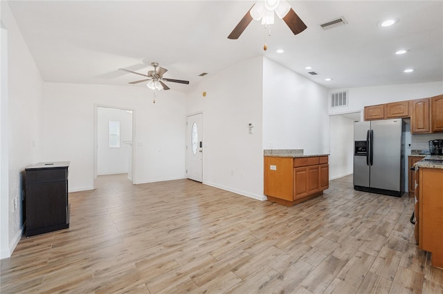 2343 St George Dr, Davenport, FL 33837 - kitchen with stainless steel fridge, ceiling fan, brown cabinetry, light wood finished floors, and lofted ceiling