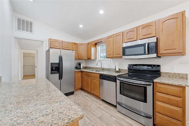 2343 St George Dr, Davenport, FL 33837 - kitchen featuring stainless steel appliances, light wood-style floors, vaulted ceiling, recessed lighting, and light stone counters