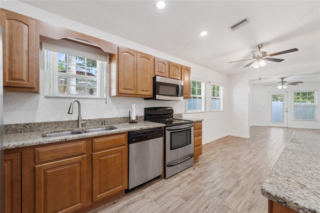 2343 St George Dr, Davenport, FL 33837 - kitchen featuring appliances with stainless steel finishes, light wood finished floors, ceiling fan, recessed lighting, and light stone counters