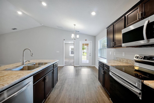 328 Lily Ln, Davenport, FL 33837 - kitchen featuring appliances with stainless steel finishes, lofted ceiling, wood finished floors, light countertops, and dark brown cabinetry