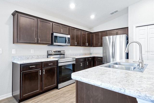 328 Lily Ln, Davenport, FL 33837 - kitchen featuring stainless steel appliances, dark brown cabinets, light wood-style floors, light countertops, and lofted ceiling