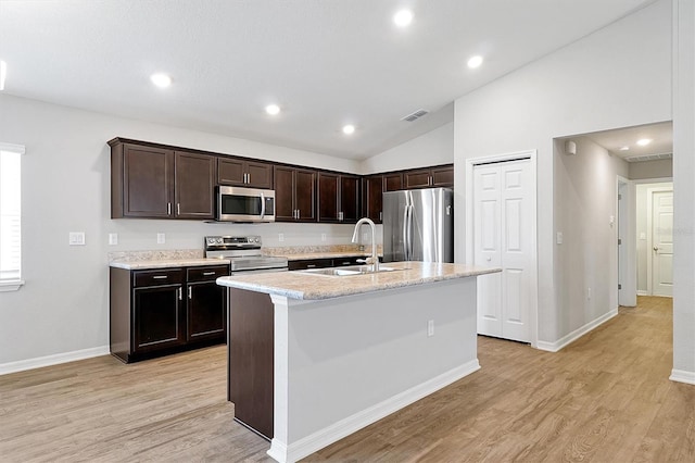 328 Lily Ln, Davenport, FL 33837 - kitchen featuring appliances with stainless steel finishes, light wood-style flooring, vaulted ceiling, dark brown cabinetry, and recessed lighting