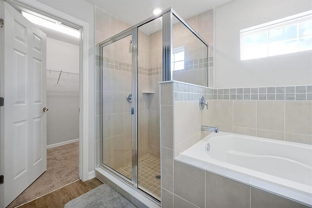 328 Lily Ln, Davenport, FL 33837 - bathroom with a stall shower, a bath, a walk in closet, and wood finished floors