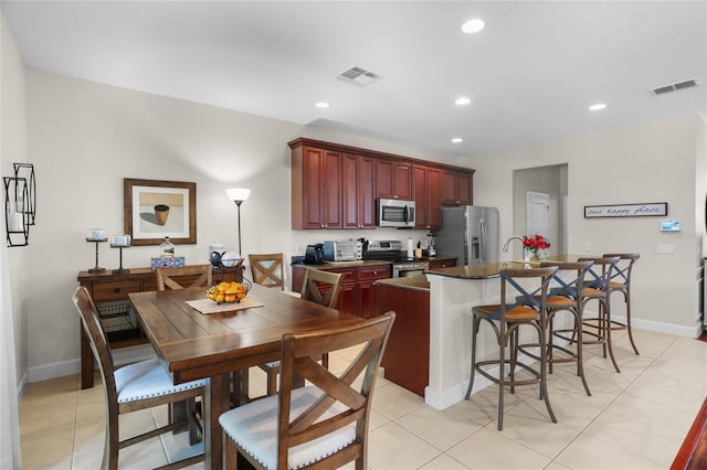 8401 Riverdale Ln Unit 8401, Davenport, FL 33896 - kitchen with stainless steel appliances, reddish brown cabinets, an island with sink, recessed lighting, and dark countertops