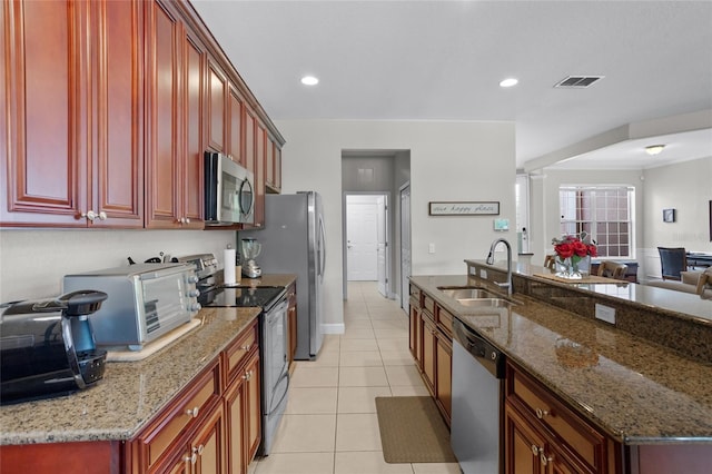 8401 Riverdale Ln Unit 8401, Davenport, FL 33896 - kitchen with stainless steel appliances, dark brown cabinets, light tile patterned flooring, open floor plan, and stone counters
