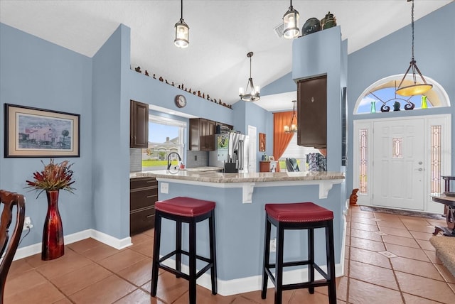 3214 Herons Point Cir, Kissimmee, FL 34741 - kitchen featuring stainless steel refrigerator with ice dispenser, lofted ceiling, a chandelier, light tile patterned floors, and a kitchen breakfast bar