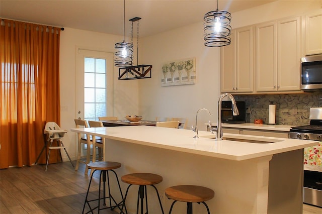 721 Benoi Dr, Davenport, FL 33896 - kitchen with stainless steel appliances, decorative backsplash, wood finished floors, a breakfast bar, and hanging light fixtures