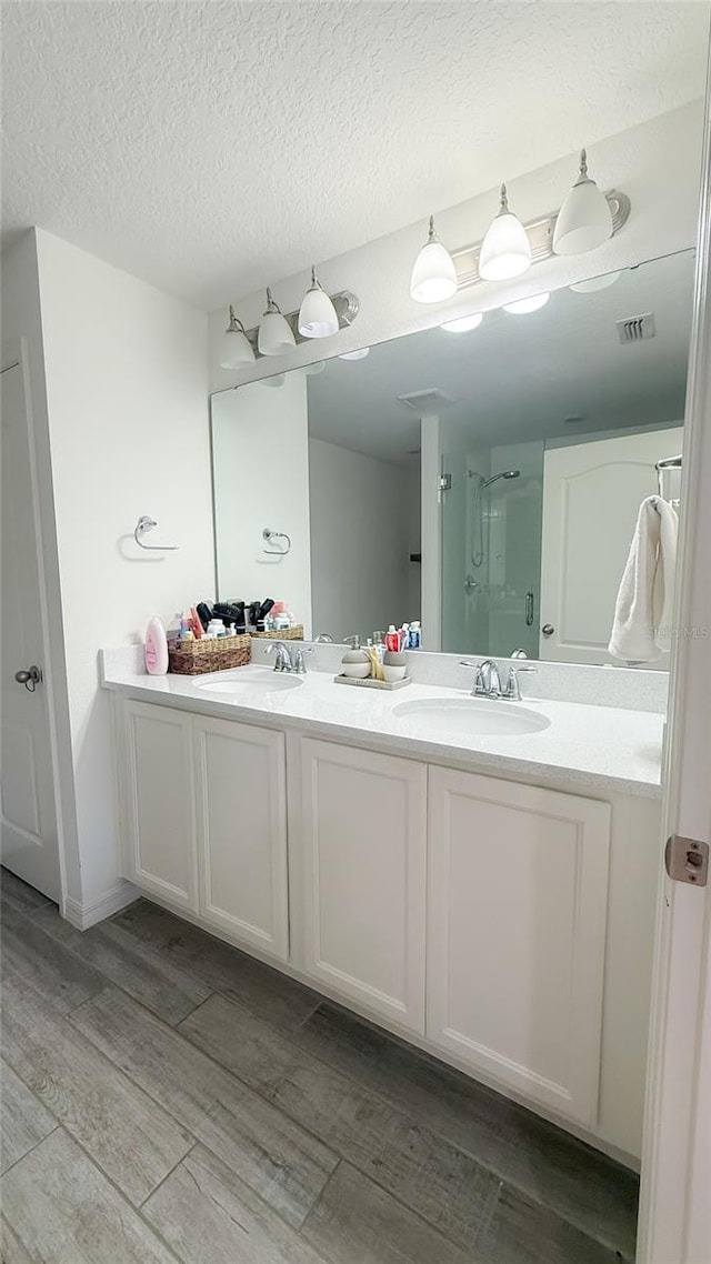 721 Benoi Dr, Davenport, FL 33896 - full bath featuring double vanity, wood finished floors, a shower with door, and a textured ceiling