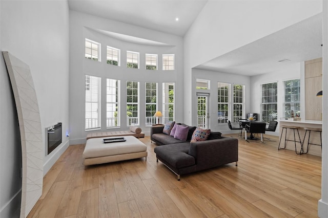 933 Jasmine St, Celebration, FL 34747 - living area featuring light wood-type flooring, a tile fireplace, plenty of natural light, and a towering ceiling