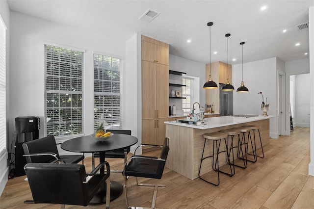 933 Jasmine St, Celebration, FL 34747 - kitchen with modern cabinets, light brown cabinets, open shelves, an island with sink, and light wood-style floors