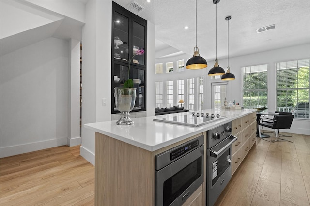 933 Jasmine St, Celebration, FL 34747 - kitchen featuring appliances with stainless steel finishes, light wood-style flooring, light countertops, a textured ceiling, and a large island