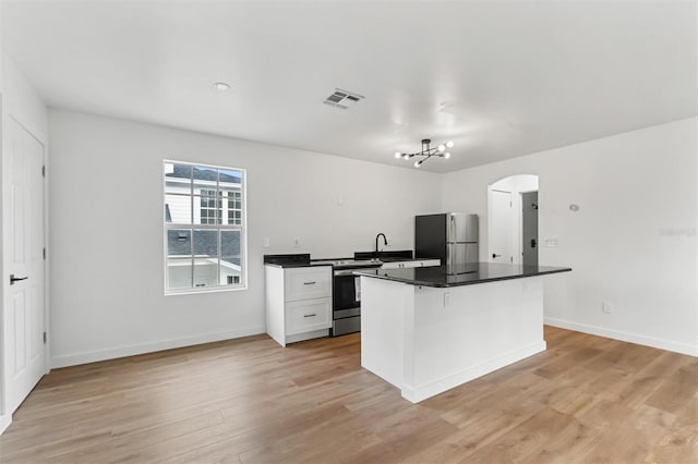 933 Jasmine St, Celebration, FL 34747 - kitchen featuring appliances with stainless steel finishes, arched walkways, light wood-style flooring, and dark countertops