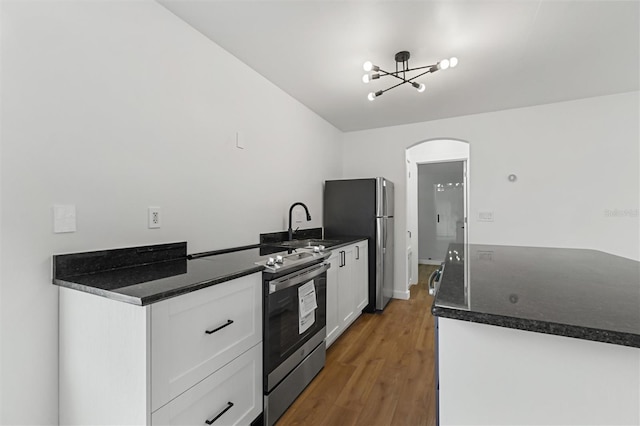 933 Jasmine St, Celebration, FL 34747 - kitchen with appliances with stainless steel finishes, arched walkways, white cabinetry, and dark countertops