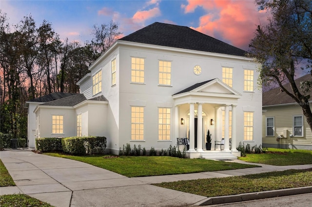 933 Jasmine St, Celebration, FL 34747 - colonial house with a porch, roof with shingles, a front yard, and stucco siding