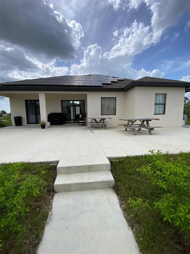 2408 Conroy Ave N, Lehigh Acres, FL 33971 - rear view of property with stucco siding, solar panels, and a patio area