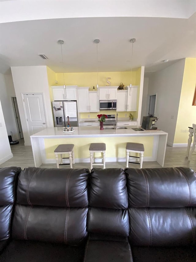 2408 Conroy Ave N, Lehigh Acres, FL 33971 - kitchen with stainless steel appliances, light countertops, white cabinets, and a breakfast bar