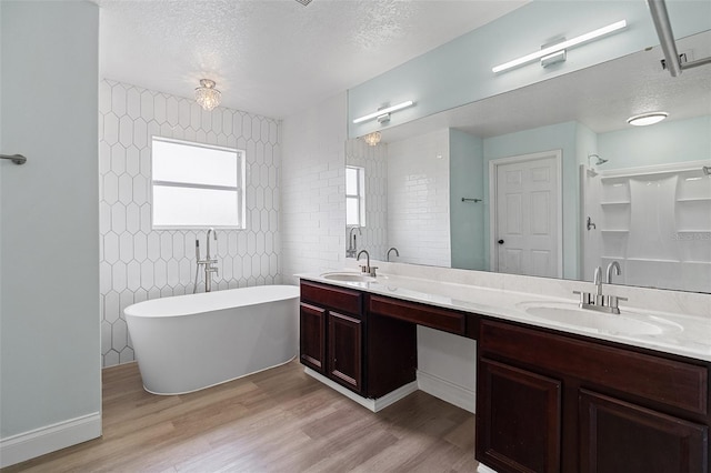 6905 Beargrass Rd, Harmony, FL 34773 - bathroom featuring double vanity, wood finished floors, a soaking tub, and a textured ceiling