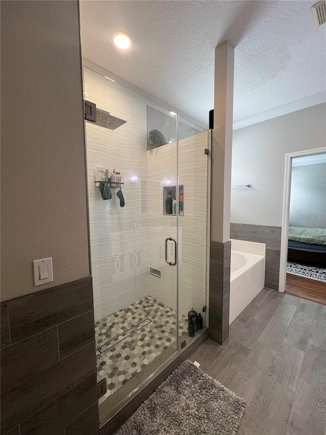 3339 Primrose Willow Dr, Saint Cloud, FL 34773 - ensuite bathroom with a bath, wood finished floors, a shower stall, and a textured ceiling