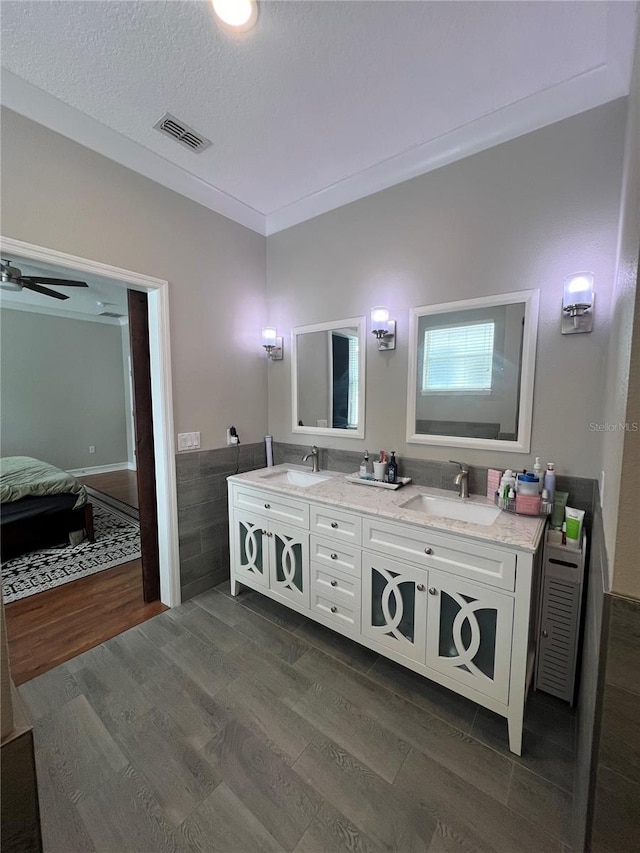 3339 Primrose Willow Dr, Saint Cloud, FL 34773 - full bathroom with double vanity, ensuite bathroom, wood finished floors, a wainscoted wall, and a textured ceiling