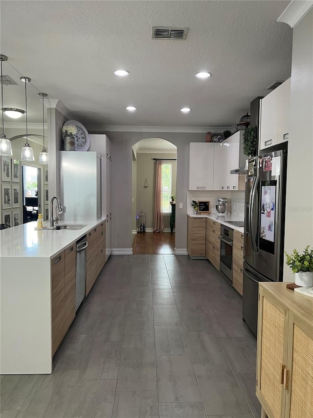 3339 Primrose Willow Dr, Saint Cloud, FL 34773 - kitchen with appliances with stainless steel finishes, arched walkways, light countertops, ornamental molding, and modern cabinets