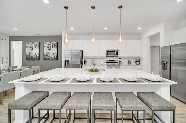 2525 Shanti Dr, Kissimmee, FL 34746 - kitchen with stainless steel appliances, white cabinets, recessed lighting, a large island, and light wood-style floors