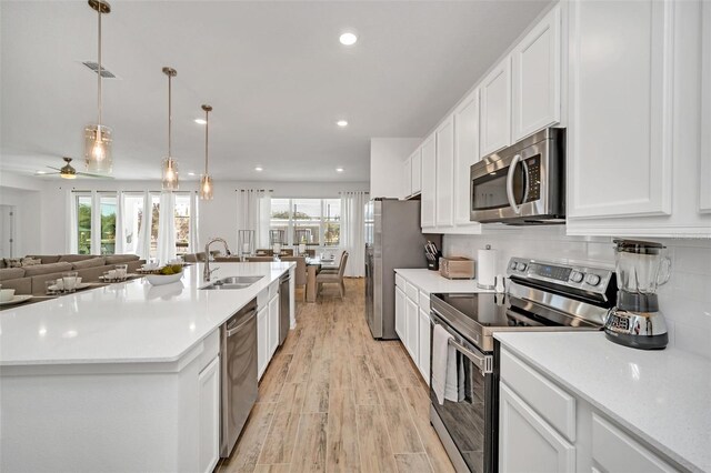 2525 Shanti Dr, Kissimmee, FL 34746 - kitchen featuring appliances with stainless steel finishes, open floor plan, light wood-style floors, white cabinets, and light countertops
