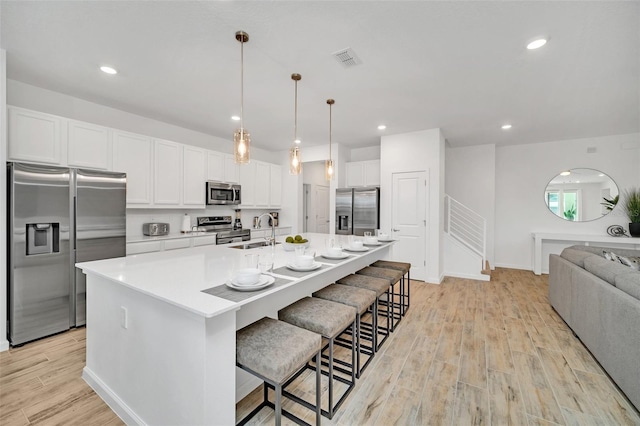 2525 Shanti Dr, Kissimmee, FL 34746 - kitchen featuring stainless steel appliances, light wood-type flooring, white cabinetry, a spacious island, and open floor plan