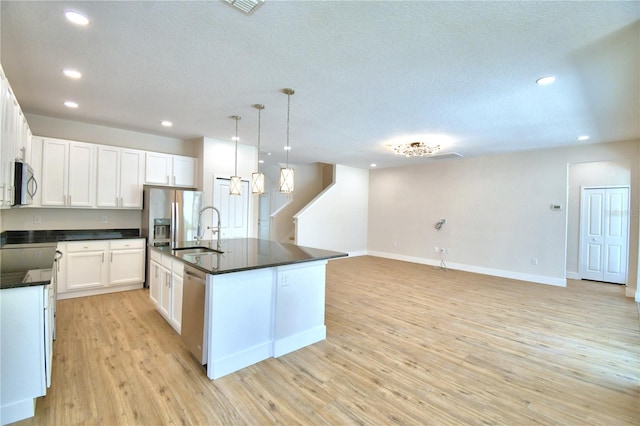 2673 Calistoga Ave, Kissimmee, FL 34741 - kitchen featuring appliances with stainless steel finishes, dark countertops, recessed lighting, light wood finished floors, and a textured ceiling