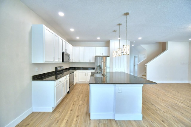 2673 Calistoga Ave, Kissimmee, FL 34741 - kitchen featuring stainless steel appliances, an island with sink, light wood finished floors, white cabinetry, and recessed lighting
