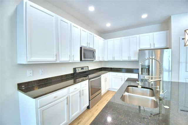 2673 Calistoga Ave, Kissimmee, FL 34741 - kitchen with appliances with stainless steel finishes, white cabinetry, recessed lighting, light wood finished floors, and dark stone countertops