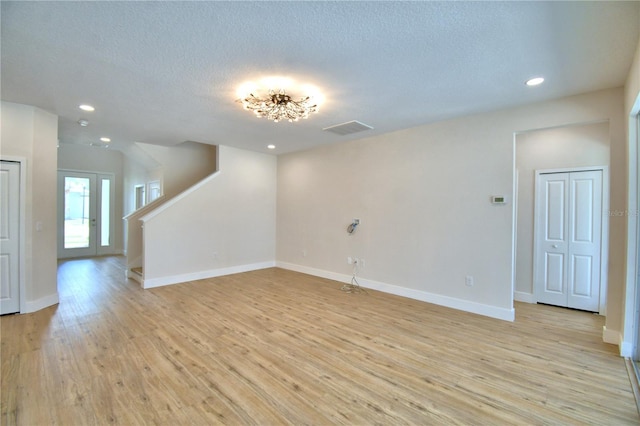 2673 Calistoga Ave, Kissimmee, FL 34741 - unfurnished living room with recessed lighting, light wood-type flooring, a textured ceiling, and stairs