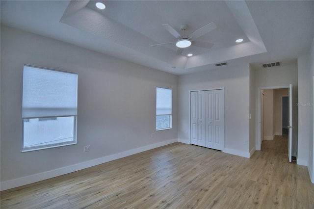 2673 Calistoga Ave, Kissimmee, FL 34741 - unfurnished bedroom featuring a raised ceiling, multiple windows, a closet, light wood-style floors, and recessed lighting