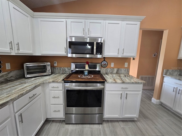 204 Canary Island Cir, Davenport, FL 33837 - kitchen featuring stainless steel appliances, white cabinets, light stone countertops, and vaulted ceiling