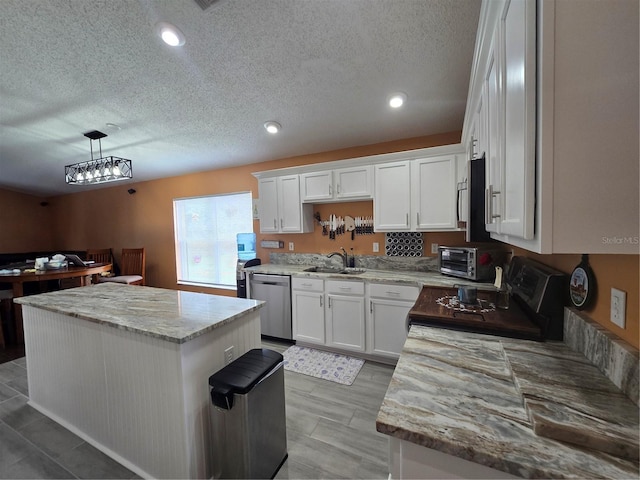 204 Canary Island Cir, Davenport, FL 33837 - kitchen with stainless steel appliances, a kitchen island, white cabinets, a textured ceiling, and light stone countertops