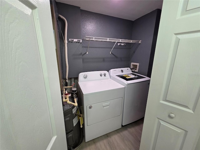 3428 Soho St Unit 208, Orlando, FL 32835 - washroom featuring washing machine and clothes dryer, light wood-type flooring, and a textured wall