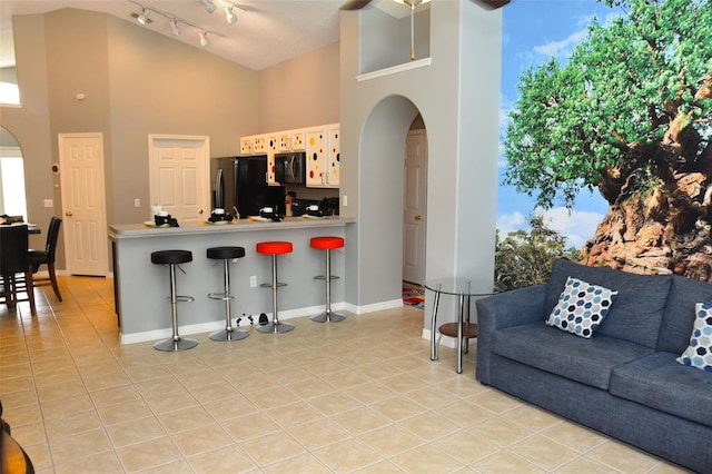 2807 Playing Otter Ct, Kissimmee, FL 34747 - kitchen featuring fridge with ice dispenser, arched walkways, black microwave, light tile patterned flooring, and a high ceiling