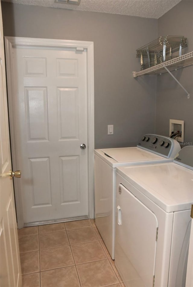 2807 Playing Otter Ct, Kissimmee, FL 34747 - laundry area featuring washing machine and dryer, light tile patterned floors, and a textured ceiling