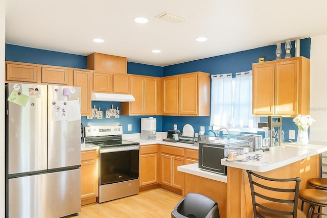 423 Midway Ave, Mascotte, FL 34753 - kitchen featuring appliances with stainless steel finishes, under cabinet range hood, light wood-style floors, a peninsula, and light countertops