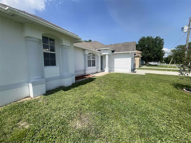 343 Marquee Dr, Kissimmee, FL 34758 - view of home's exterior featuring a yard, stucco siding, a garage, and a shingled roof
