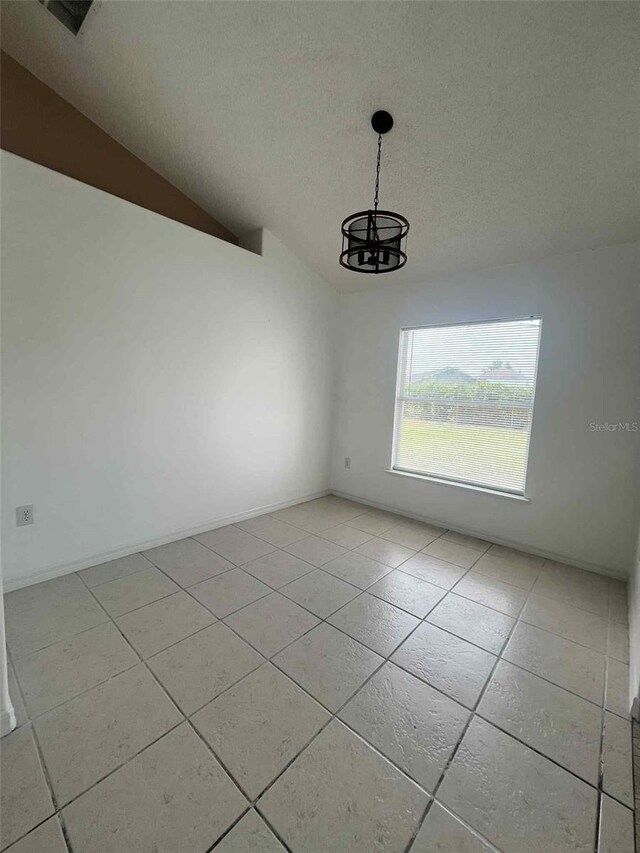 343 Marquee Dr, Kissimmee, FL 34758 - spare room featuring a textured ceiling, light tile patterned floors, a chandelier, and vaulted ceiling