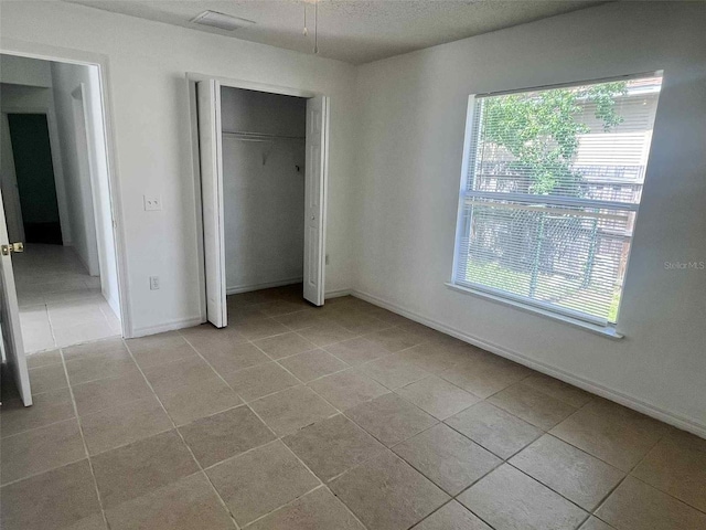 343 Marquee Dr, Kissimmee, FL 34758 - unfurnished bedroom featuring light tile patterned floors, a closet, and a textured ceiling