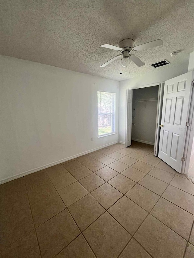 343 Marquee Dr, Kissimmee, FL 34758 - unfurnished bedroom featuring light tile patterned floors, a textured ceiling, a closet, and a ceiling fan