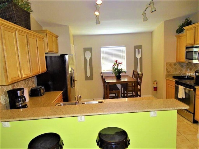 2281 Royal Ridge Dr, Davenport, FL 33896 - kitchen featuring appliances with stainless steel finishes, light tile patterned floors, decorative backsplash, a peninsula, and light countertops