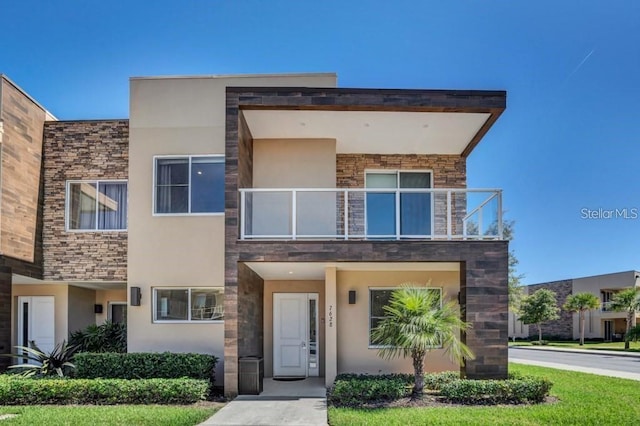 7628 Recife Dr, Kissimmee, FL 34747 - contemporary house with a balcony, stone siding, and stucco siding