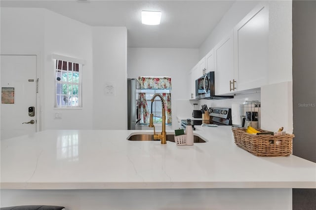 1129 Park Ridge Cir, Kissimmee, FL 34746 - kitchen featuring stainless steel appliances, light stone countertops, white cabinetry, and a peninsula