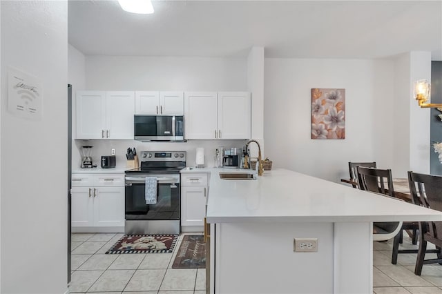 1129 Park Ridge Cir, Kissimmee, FL 34746 - kitchen featuring appliances with stainless steel finishes, a peninsula, light tile patterned floors, and light countertops