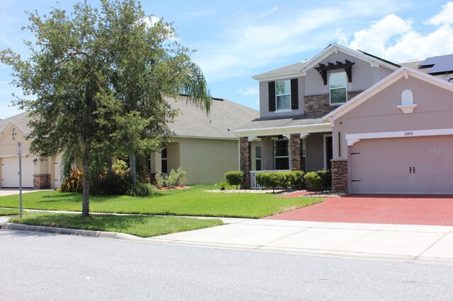 2805 Carter Grove Ln, Kissimmee, FL 34741 - view of front facade featuring stone siding, stucco siding, decorative driveway, a front lawn, and a garage
