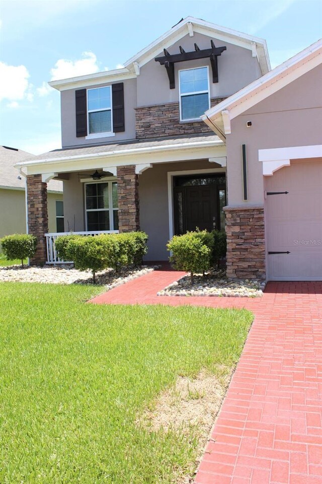2805 Carter Grove Ln, Kissimmee, FL 34741 - view of front of house with stucco siding, stone siding, a front yard, covered porch, and an attached garage